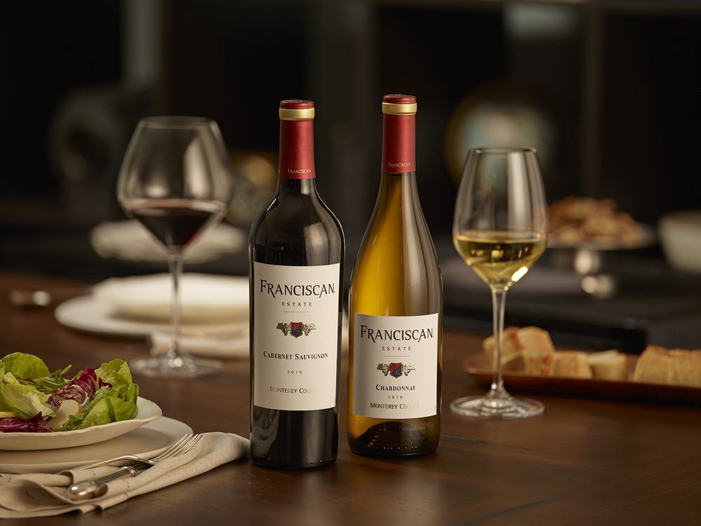 Cabernet and Chardonnay bottle on table with stemware.